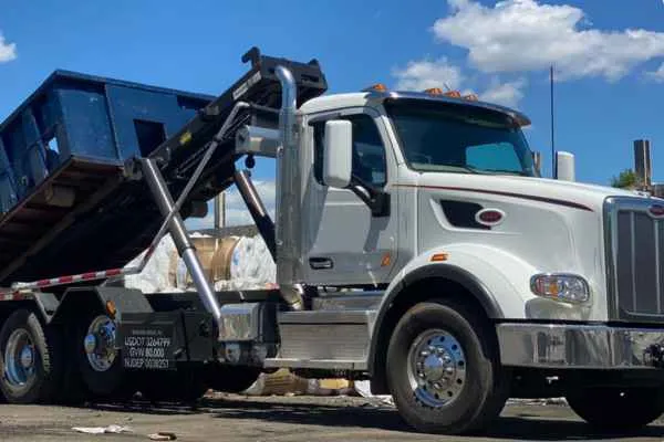 close up of a roll off truck with trash in background