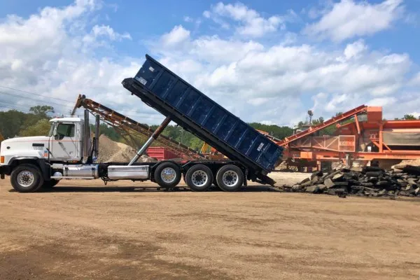 roll off truck dropping off dumpster on construction site