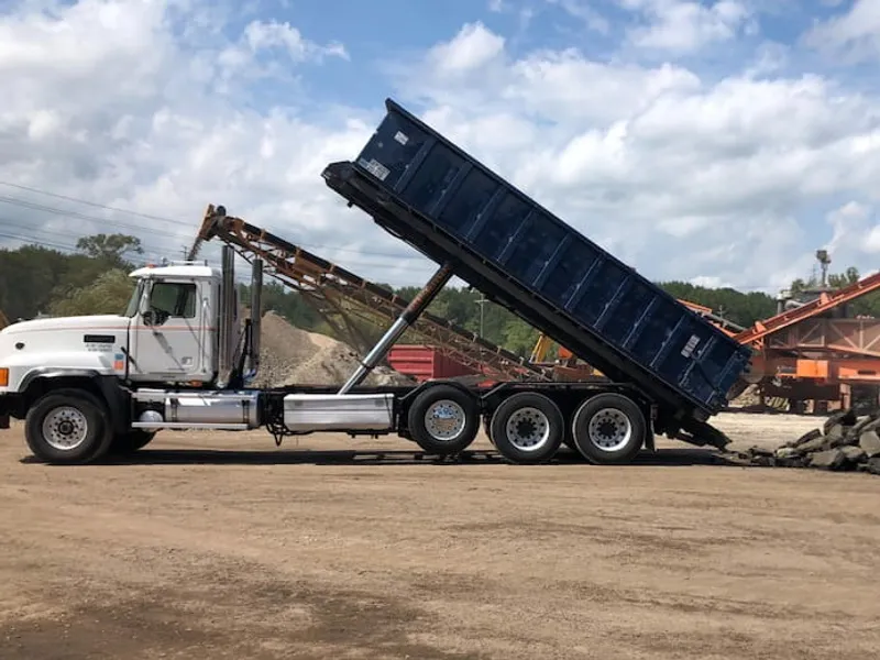 A roll off truck dumping a 20 yard dumpster