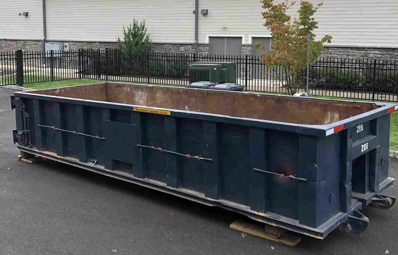 Blue roll off bin behind gated fence