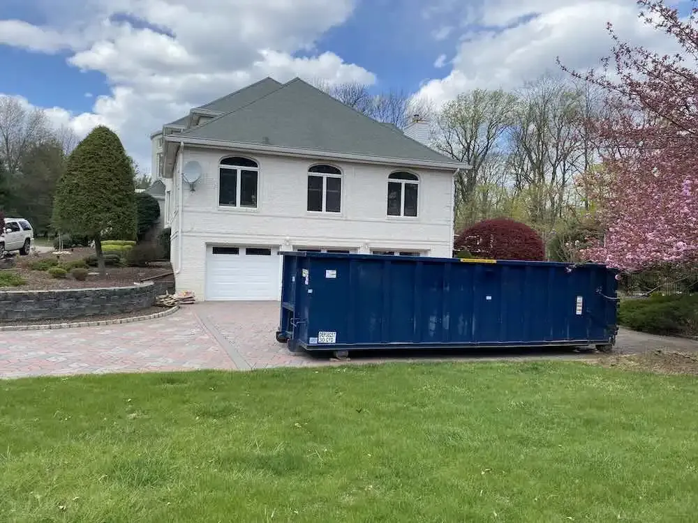 dumpster on driveway with pink flowers