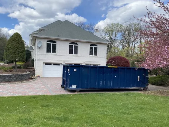 30 yard blue roll off dumpster in driveway with house and cherry blossom